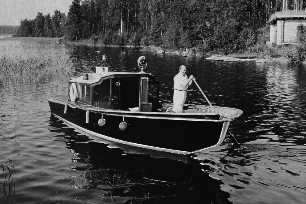 Alvar Aalto ohjaa venettään Muuratsalon rannassa 1950-luvulla. Alvar Aalto and the Nemo propheta in patria boat at Muuratsalo. Photo Pellervo Oksala, Alvar Aalto Foundation. AR 53-1